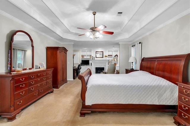 bedroom with a fireplace, a raised ceiling, light carpet, and visible vents