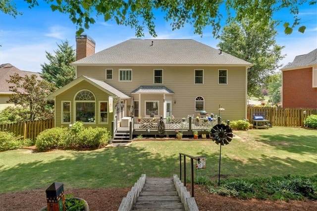 back of property with a lawn, fence, a wooden deck, and a chimney