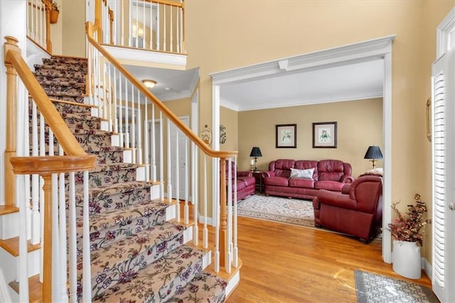 stairs featuring plenty of natural light, ornamental molding, and wood finished floors