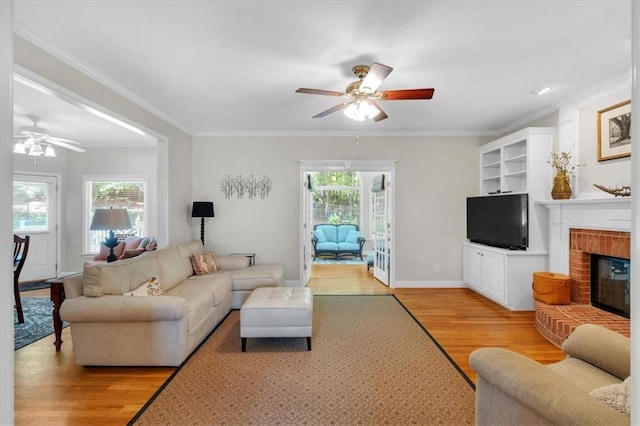 living room featuring ceiling fan, ornamental molding, and light wood finished floors