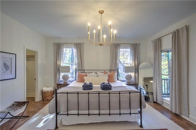 bedroom with an inviting chandelier, access to exterior, a walk in closet, and multiple windows