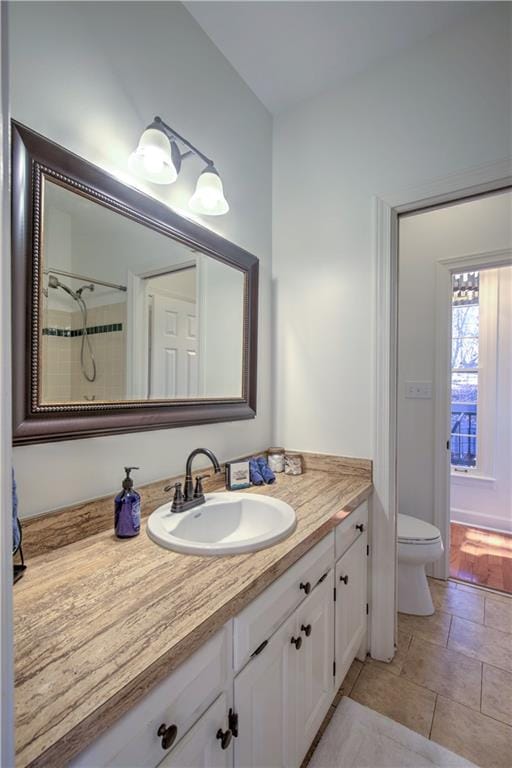 bathroom with a tile shower, vanity, and toilet