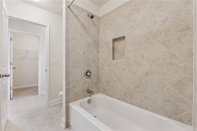 full bath with toilet, shower / washtub combination, baseboards, and a walk in closet