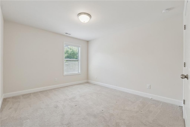 empty room with light carpet, baseboards, and a smoke detector