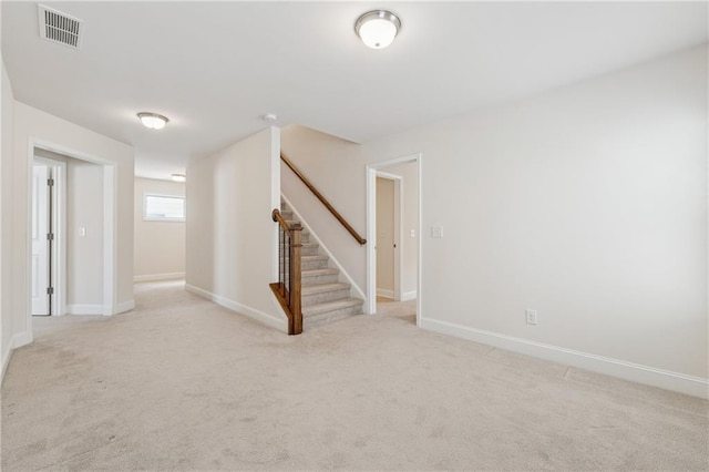 unfurnished room with light carpet, stairway, and baseboards