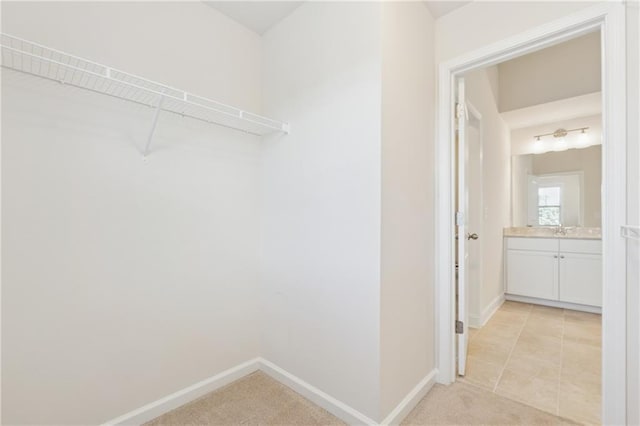 spacious closet with light colored carpet and a sink