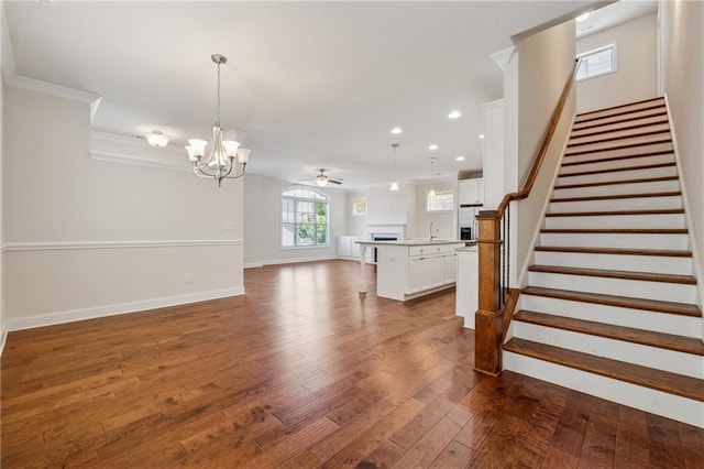 stairs featuring a chandelier, crown molding, ceiling fan, wood finished floors, and recessed lighting