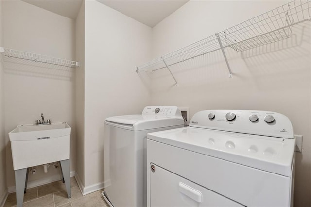laundry area with washer and clothes dryer, baseboards, and light tile patterned flooring