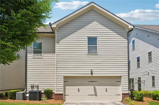 view of home's exterior with a garage, concrete driveway, central AC unit, and brick siding
