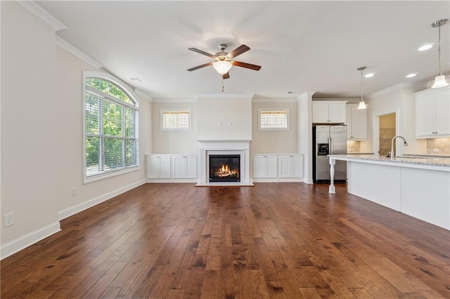 unfurnished living room with dark wood finished floors, ceiling fan, crown molding, a glass covered fireplace, and recessed lighting