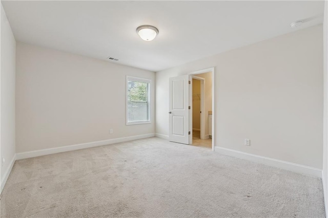 empty room with light colored carpet, baseboards, and a smoke detector