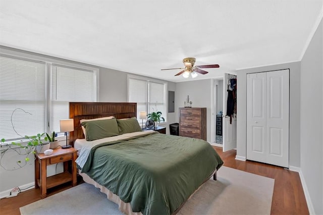 bedroom with baseboards, wood finished floors, a ceiling fan, and electric panel
