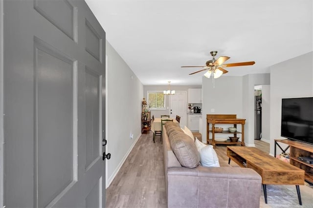 living room featuring a chandelier, light wood-style floors, ceiling fan, and baseboards