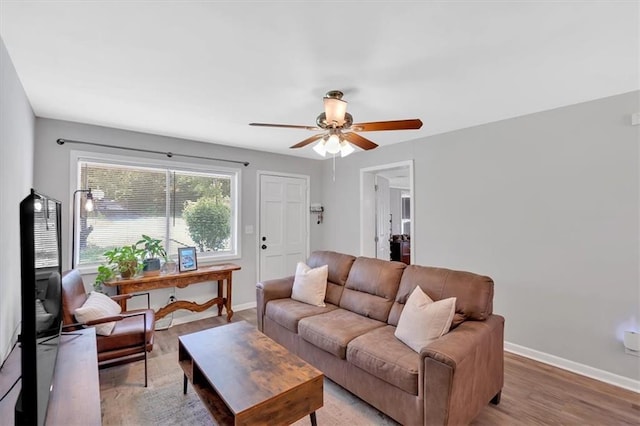 living area featuring a ceiling fan, baseboards, and light wood-style flooring