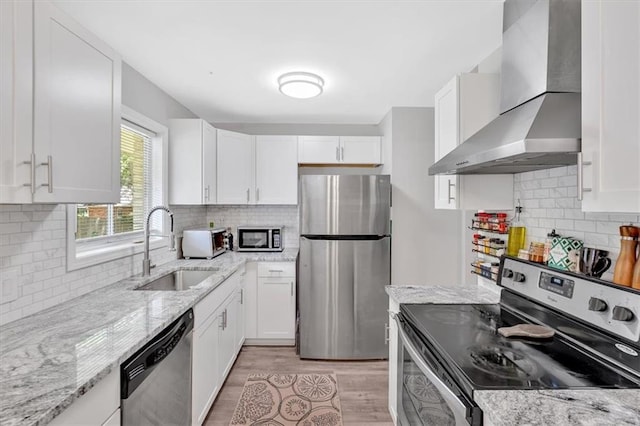 kitchen with stainless steel appliances, wall chimney range hood, a sink, and backsplash