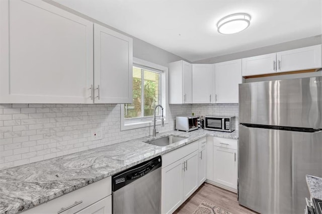 kitchen featuring stainless steel appliances, a sink, and white cabinetry