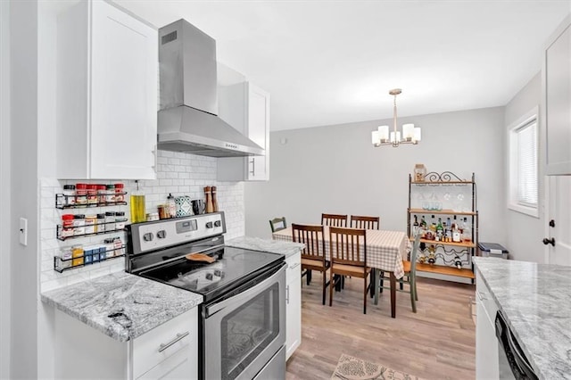 kitchen featuring appliances with stainless steel finishes, wall chimney exhaust hood, a chandelier, white cabinets, and tasteful backsplash