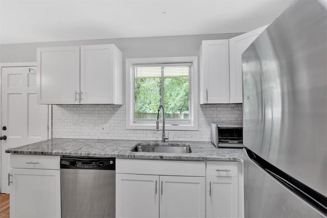 kitchen featuring stainless steel appliances, a sink, white cabinets, and light stone counters