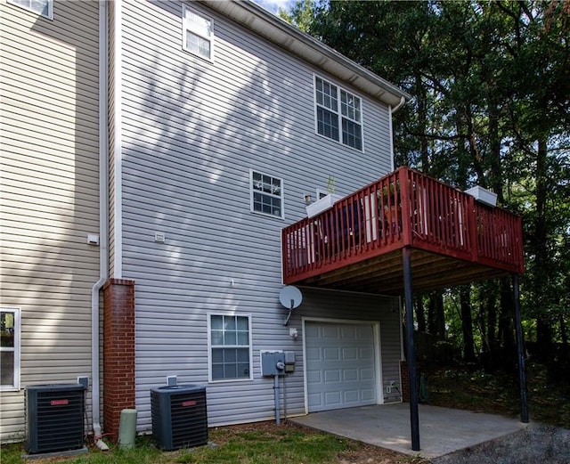 rear view of property with a garage, a wooden deck, and central AC