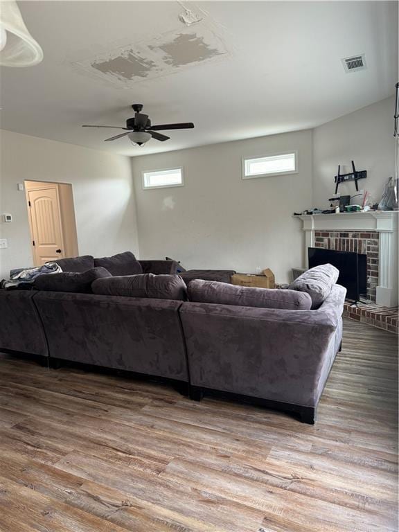 living room featuring hardwood / wood-style flooring, ceiling fan, and a brick fireplace