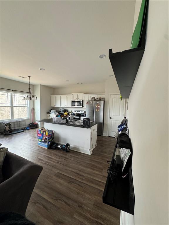 kitchen featuring white cabinetry, appliances with stainless steel finishes, dark hardwood / wood-style floors, and hanging light fixtures