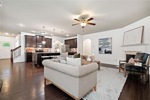 123 Meridian Dr, Woodstock, GA 30188 - living room featuring arched walkways, dark wood-type flooring, a ceiling fan, baseboards, and a fireplace