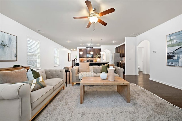 123 Meridian Dr, Woodstock, GA 30188 - living room featuring wood finished floors, arched walkways, a ceiling fan, stairs, and baseboards
