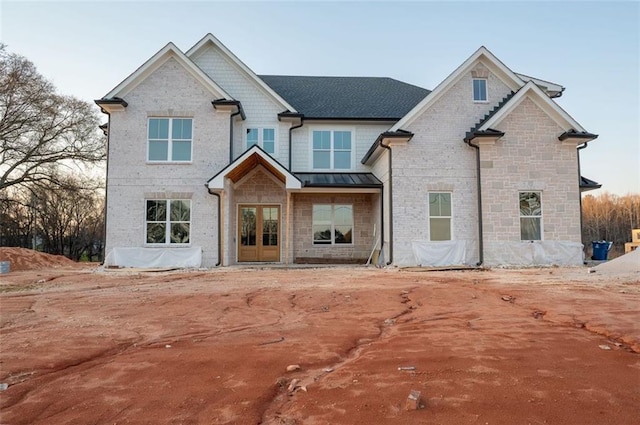 view of front of home with french doors, brick siding, metal roof, and a standing seam roof