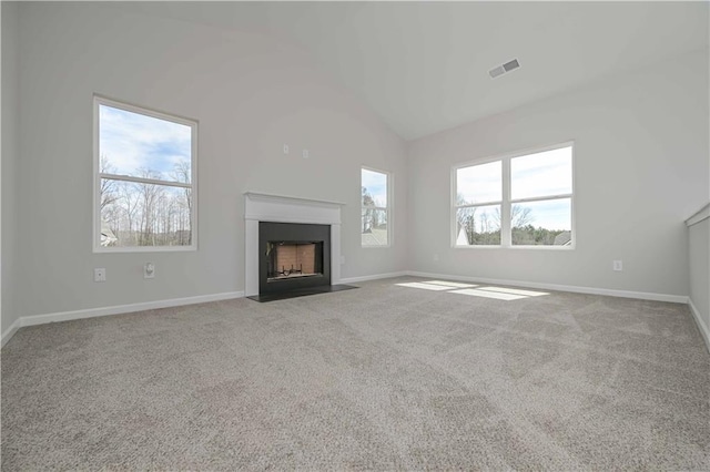 unfurnished living room featuring carpet, vaulted ceiling, baseboards, visible vents, and a fireplace with flush hearth