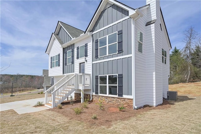 view of front of property featuring a chimney, board and batten siding, driveway, and stone siding