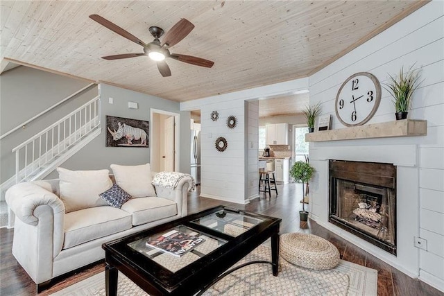 living room featuring wooden ceiling, wood walls, a fireplace, wood finished floors, and stairs