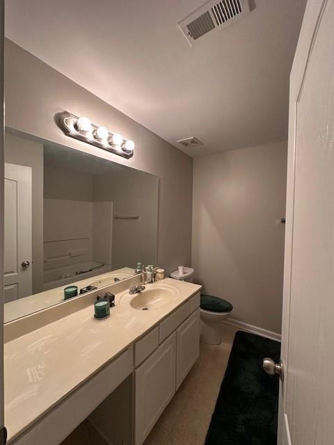 bathroom with toilet, vanity, tile patterned flooring, baseboards, and visible vents