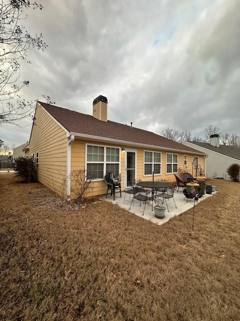 back of property with a chimney, a yard, and a patio