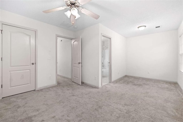 unfurnished bedroom with ceiling fan, light colored carpet, a textured ceiling, and a closet