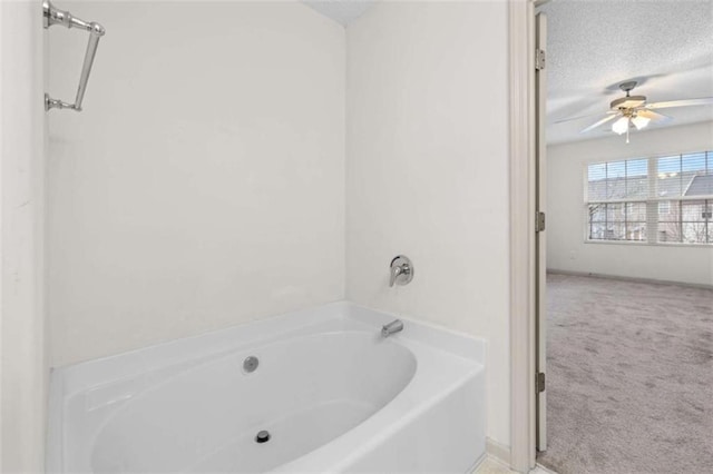 bathroom featuring a tub, ceiling fan, and a textured ceiling