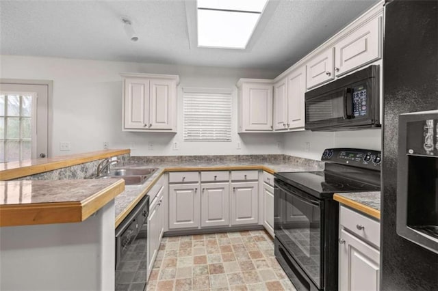 kitchen featuring black appliances, white cabinets, kitchen peninsula, and sink