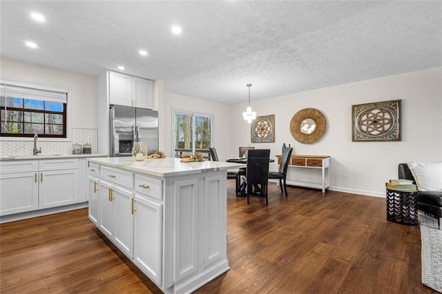 kitchen featuring dark wood-style flooring, stainless steel fridge, white cabinetry, and a sink