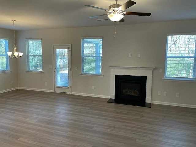 unfurnished living room with ceiling fan with notable chandelier and dark hardwood / wood-style flooring