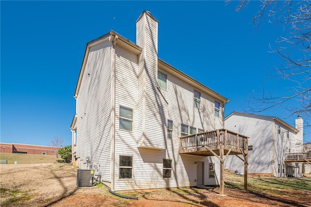 rear view of house featuring a deck, central AC, and a chimney