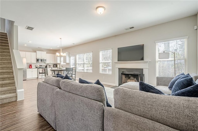 living room with a wealth of natural light, visible vents, and stairs