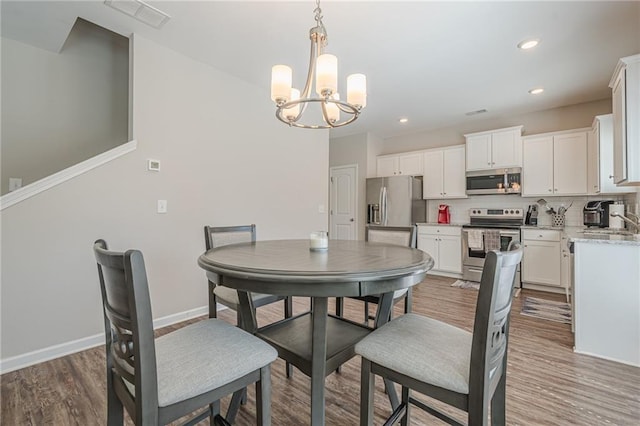 dining space featuring visible vents, baseboards, a chandelier, recessed lighting, and wood finished floors