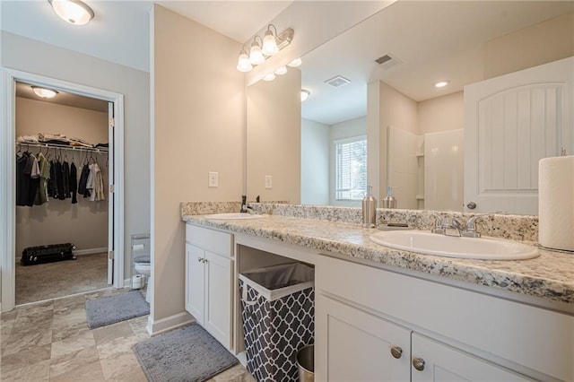 bathroom featuring double vanity, toilet, visible vents, and a sink