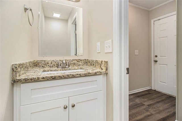 bathroom featuring hardwood / wood-style floors, vanity, and ornamental molding