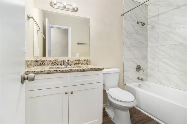 full bathroom featuring hardwood / wood-style flooring, tiled shower / bath combo, toilet, and vanity