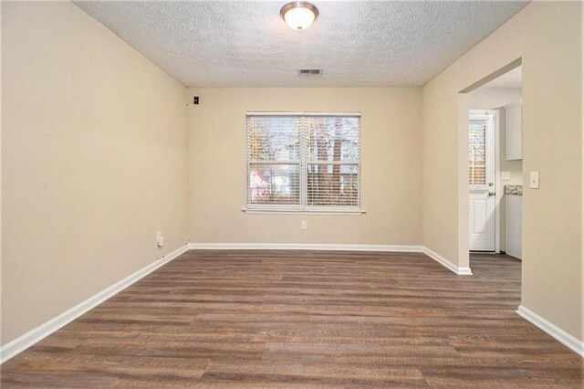 unfurnished room featuring a textured ceiling, dark hardwood / wood-style flooring, and plenty of natural light