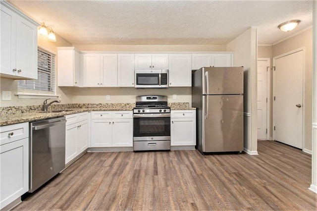 kitchen featuring white cabinets, sink, appliances with stainless steel finishes, dark hardwood / wood-style flooring, and light stone counters