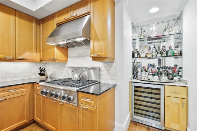 bar featuring tasteful backsplash, wine cooler, a bar, under cabinet range hood, and stainless steel gas stovetop