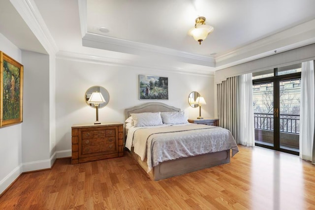 bedroom with access to exterior, a tray ceiling, ornamental molding, and light wood-style floors