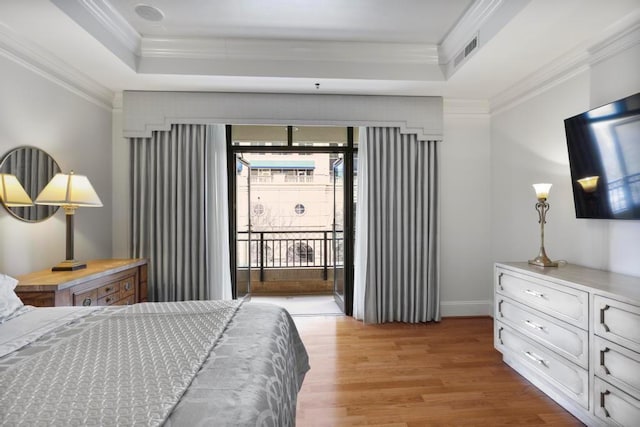 bedroom with ornamental molding, a tray ceiling, and access to exterior