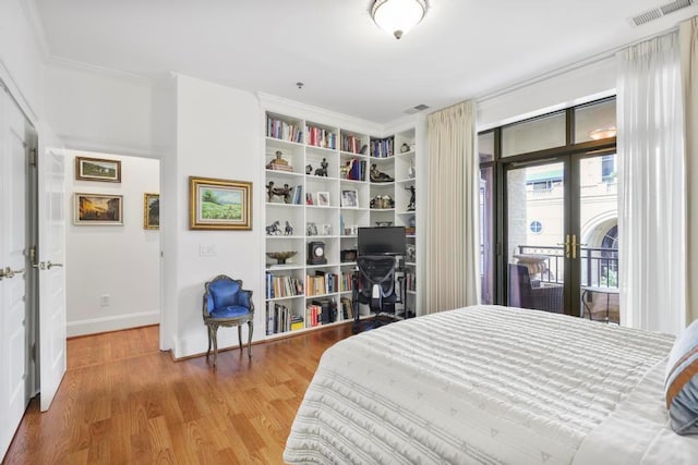 bedroom with wood finished floors, visible vents, access to outside, french doors, and crown molding